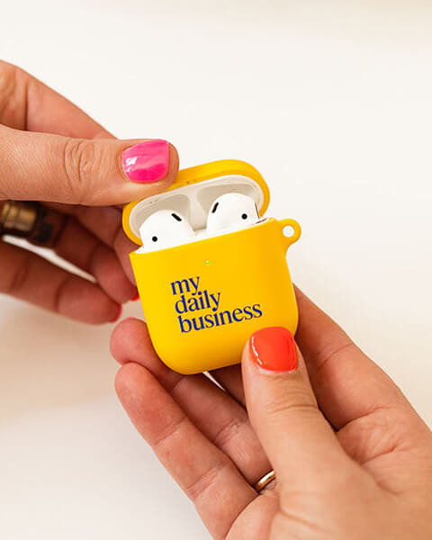 hands holding an airpods case with a my daily business branded cover
